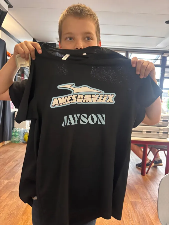 Jongen toont zijn shirt met logo en naam