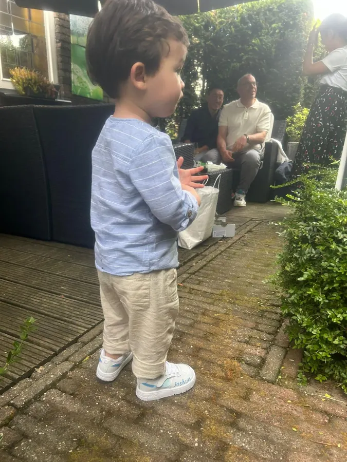 Peuter op nieuwe witte sneakers in de tuin