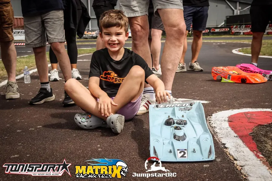 Jonge racer in custom shirt bij zijn auto