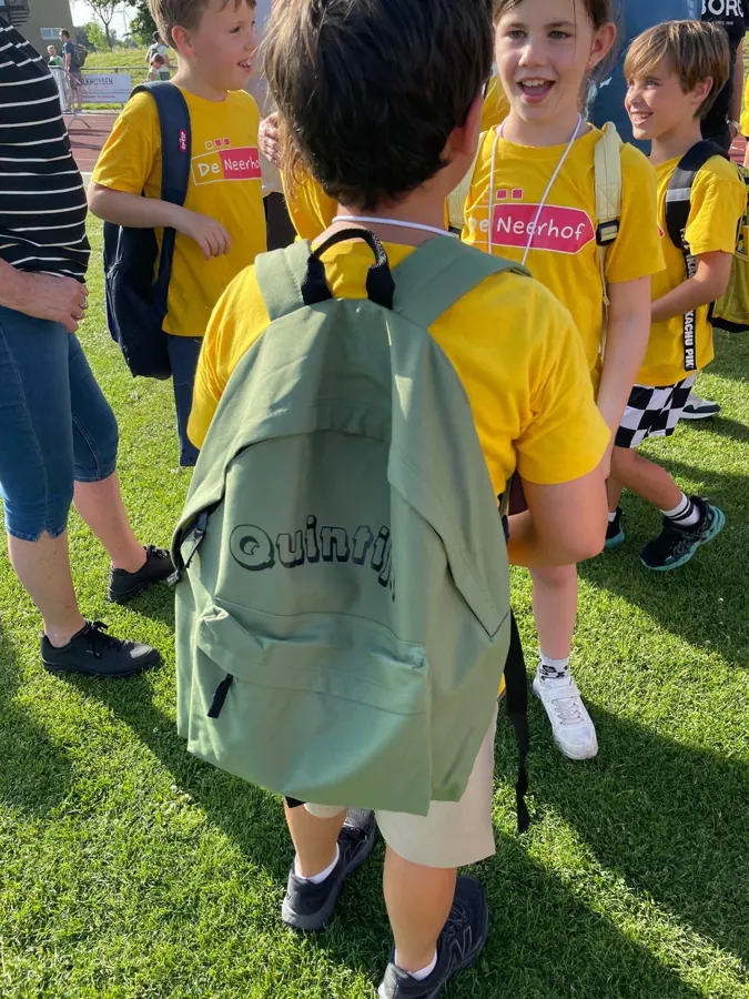 Kinderen in gele groepsshirts met rugzak met naam