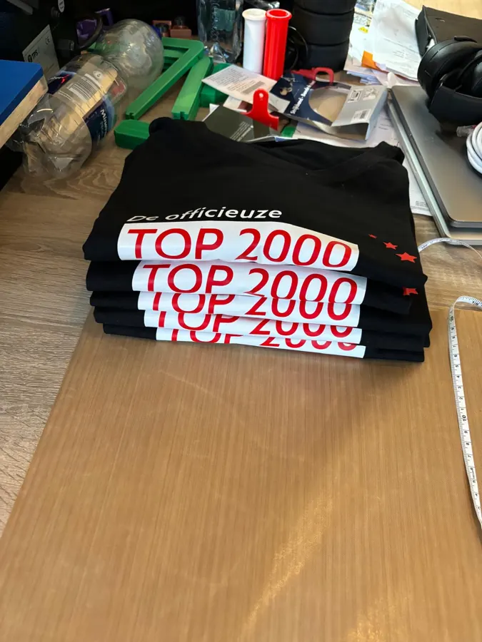 Stapel zwarte shirts met Top 2000-opdruk