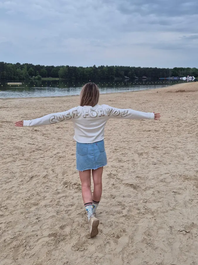 Witte trui met Cusz for You op de mouwen, op het strand