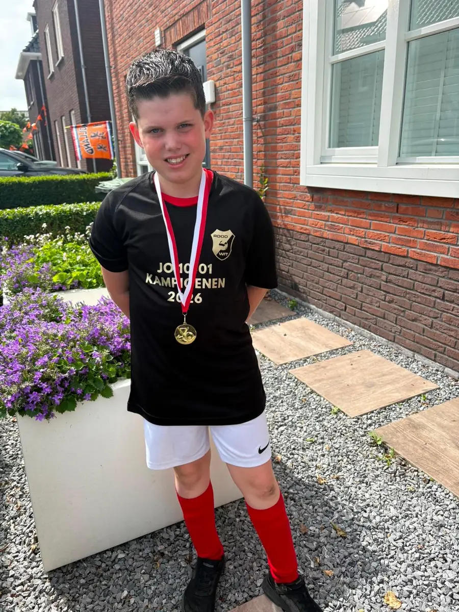 Jonge voetballer in zwart kampioensshirt met medaille